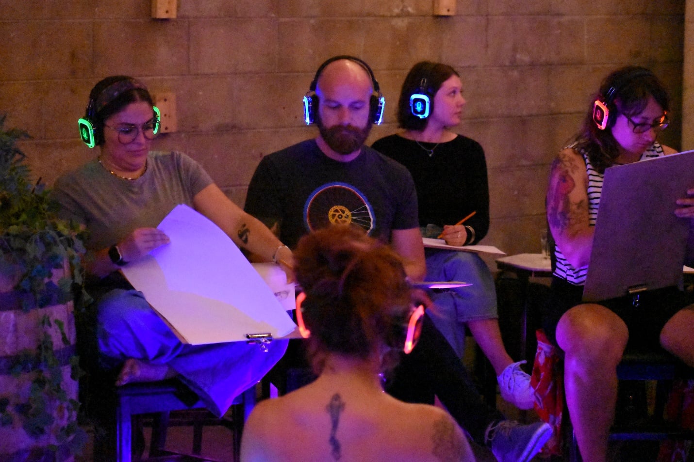 Participants wearing glowing silent disco headphones while sketching at a Sketch & Sip event