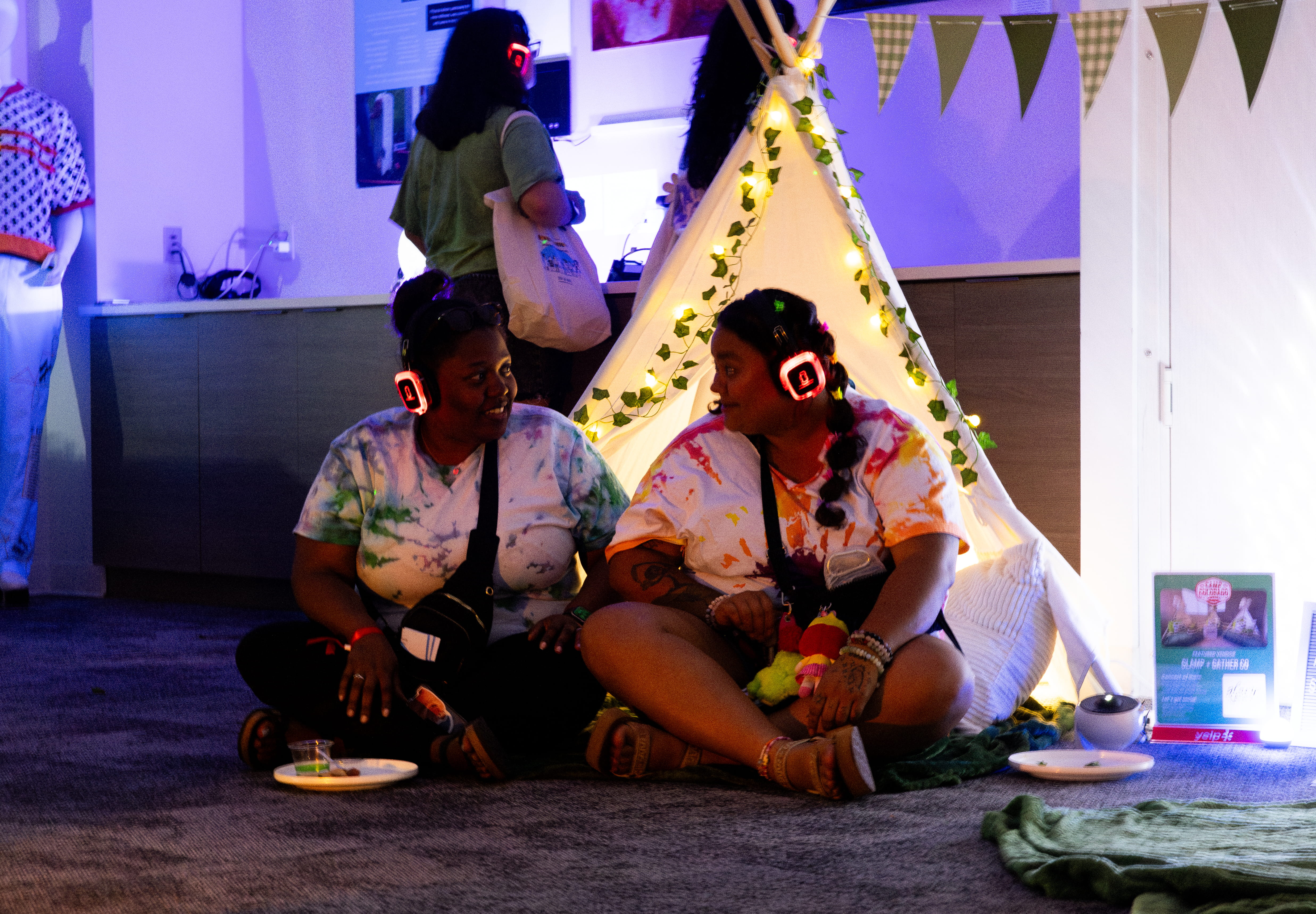 Wide shot of the Silent Disco Decompression Room with tents, telescope projection, and guests wearing headphones