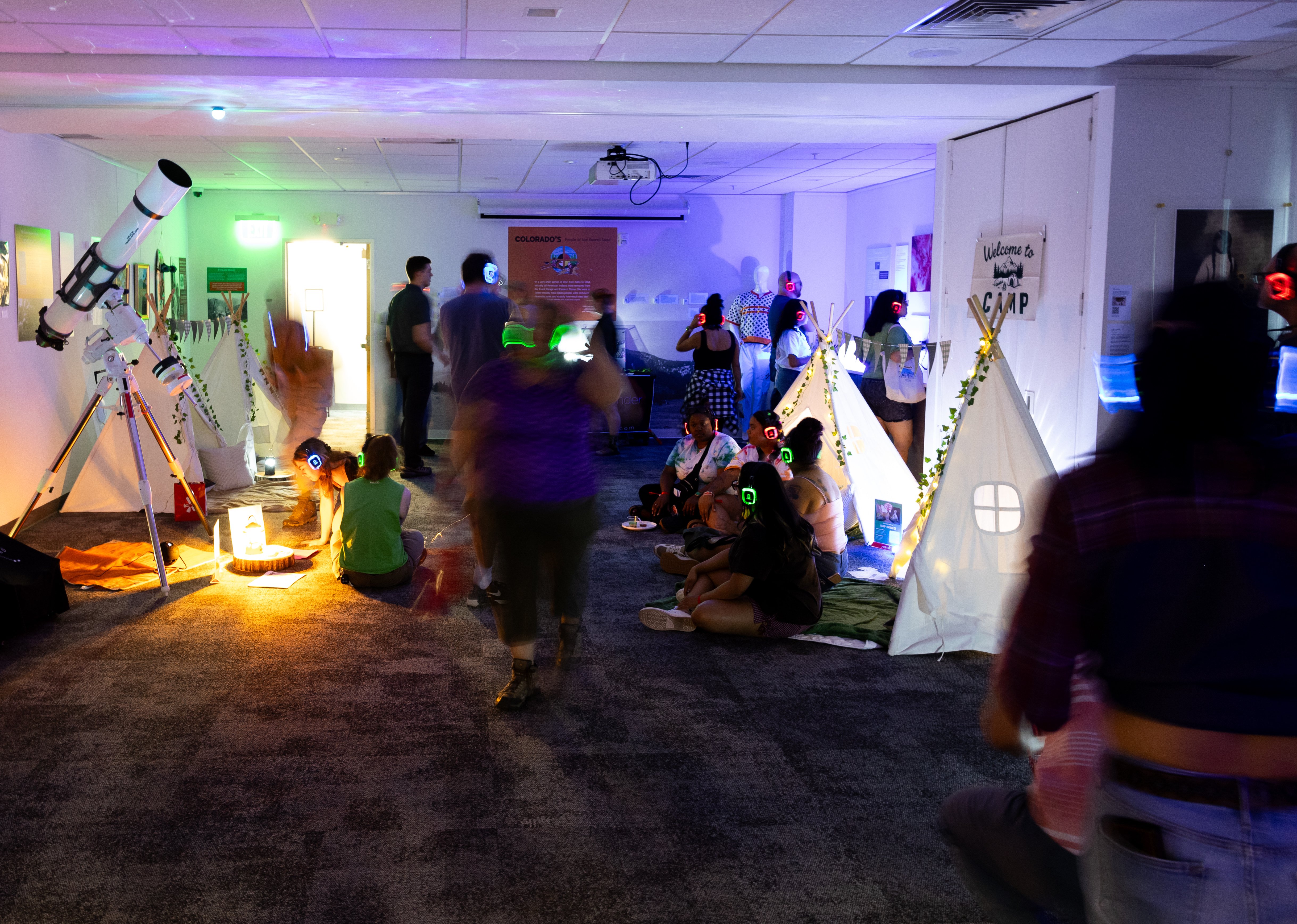 Guests lying inside glamping tents wearing glowing silent disco headphones with stars projected on the ceiling