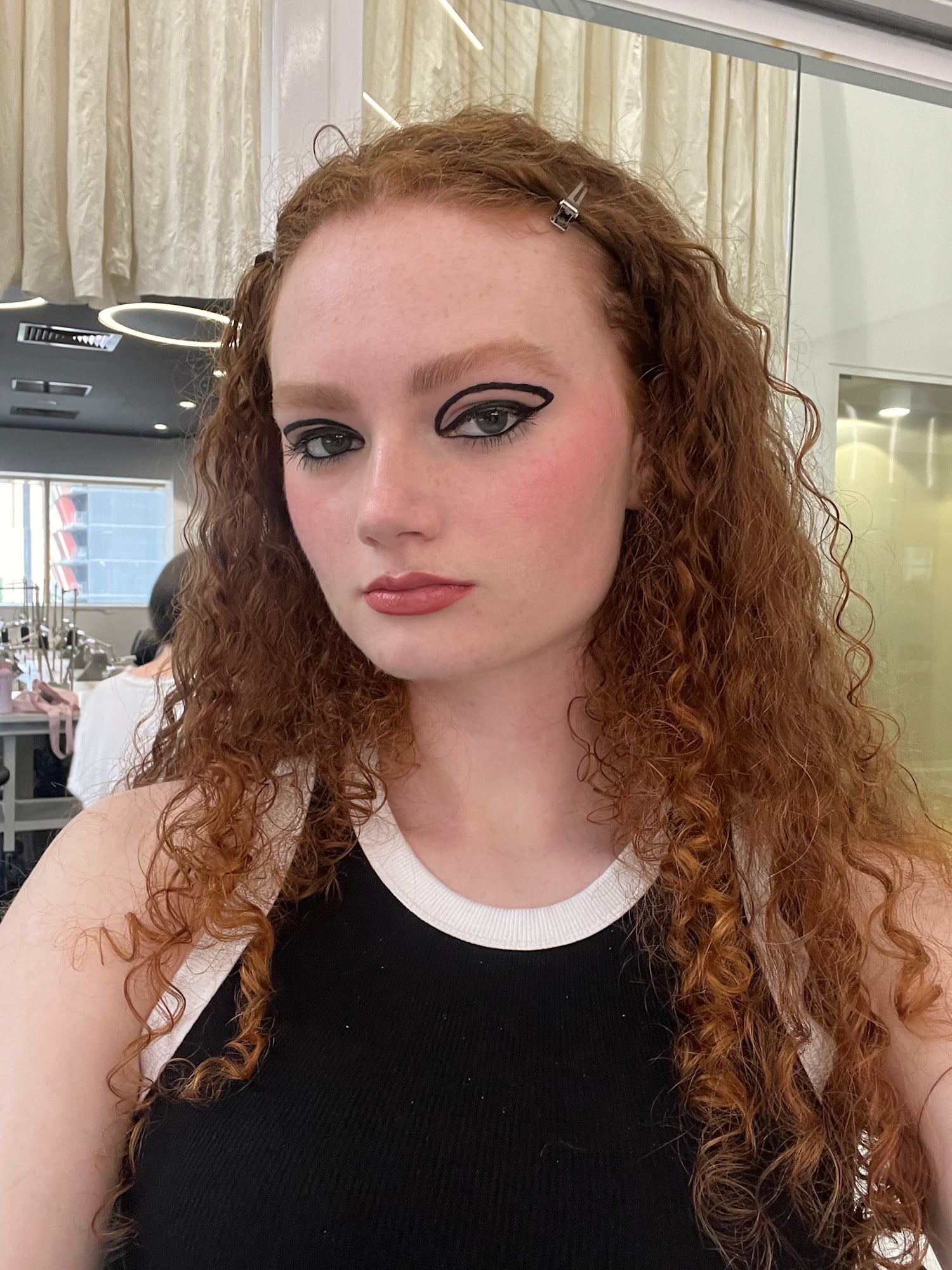 Sharp black graphic liner with a pink blush wash and red curls